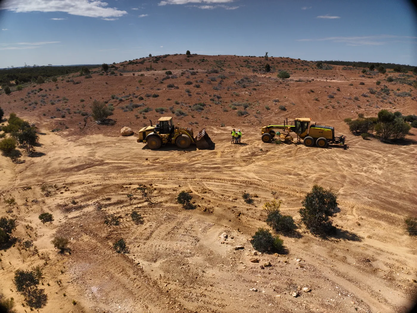 Personnel standing between a loader and a grader at Holleton